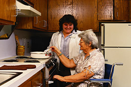 Caregiver helping client in a wheelchair prepare a meal