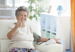 Happy senior woman taking blood pressure