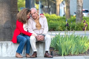 Adult daughter comforting her senior father on a sidewalk