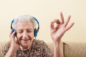senior woman making okay sign while wearing headphones to listening music - technology for seniors