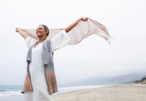 Senior woman smiling and feeling the wind on a beach