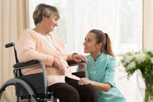 Woman in wheelchair smiling at her caregiver