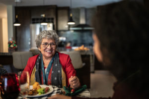 An older woman enjoys a holiday meal with her family. During holiday visits, it’s not uncommon to notice increased care needs for aging parents.