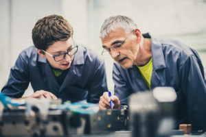 Older adult wisdom is imparted as a man shares his expertise with a young professional.