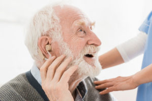 An older man who knows the connections between hearing loss and dementia is fitted for hearing aids.