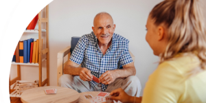 A companion care aide plays cards with an older adult at home.