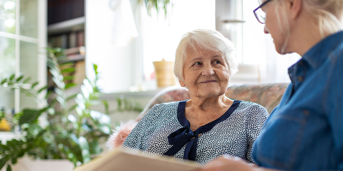 Two women look through a photo album, a common activity during dementia care at home.