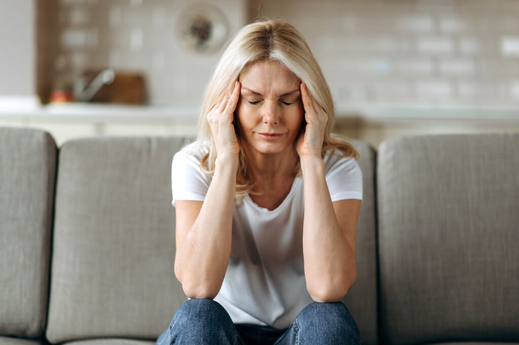 An overwhelmed family caregiver holds her head in her hands.