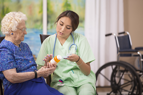 A nurse reviews medications with an older woman at home to prevent the dangers of medication mishaps.