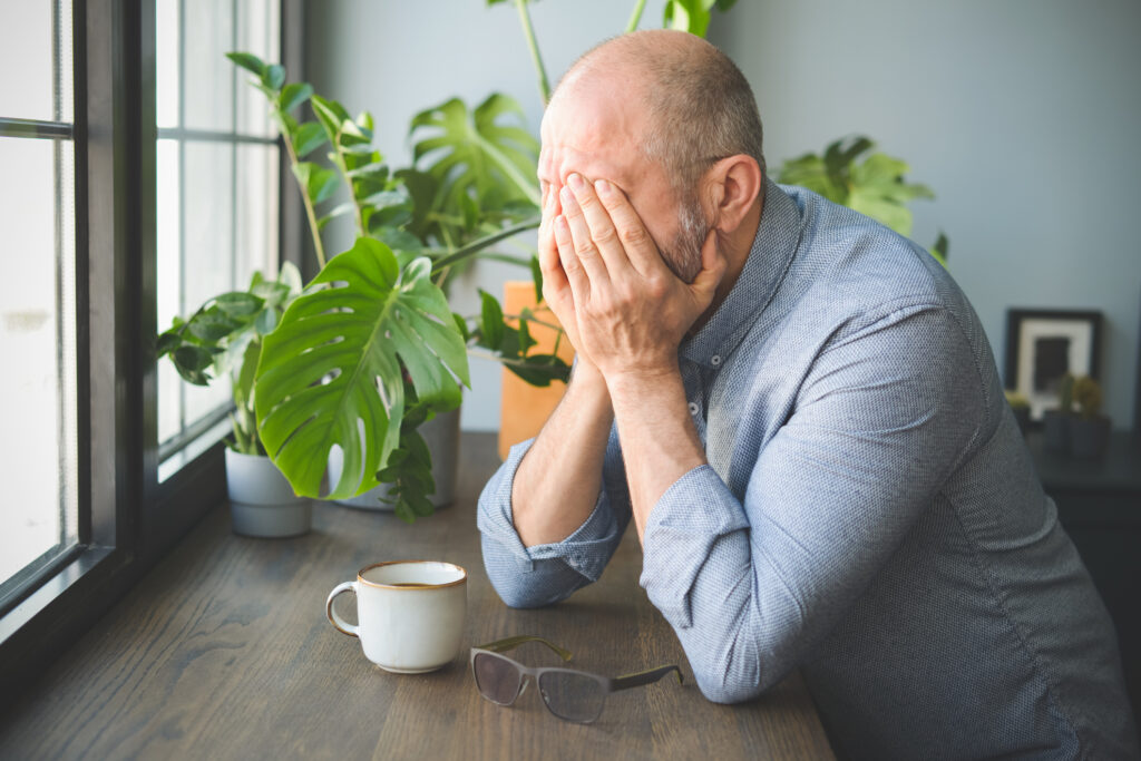 A man experiencing PTSD later in life covers his face with his hands.