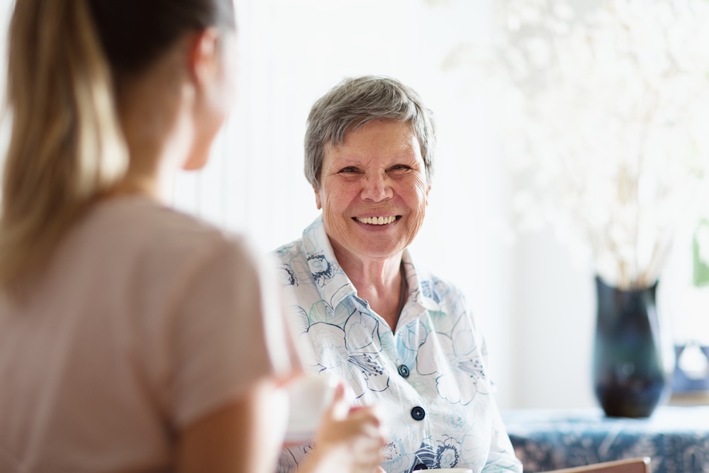 A woman with Alzheimer’s and heart disease smiles at her caregiver.