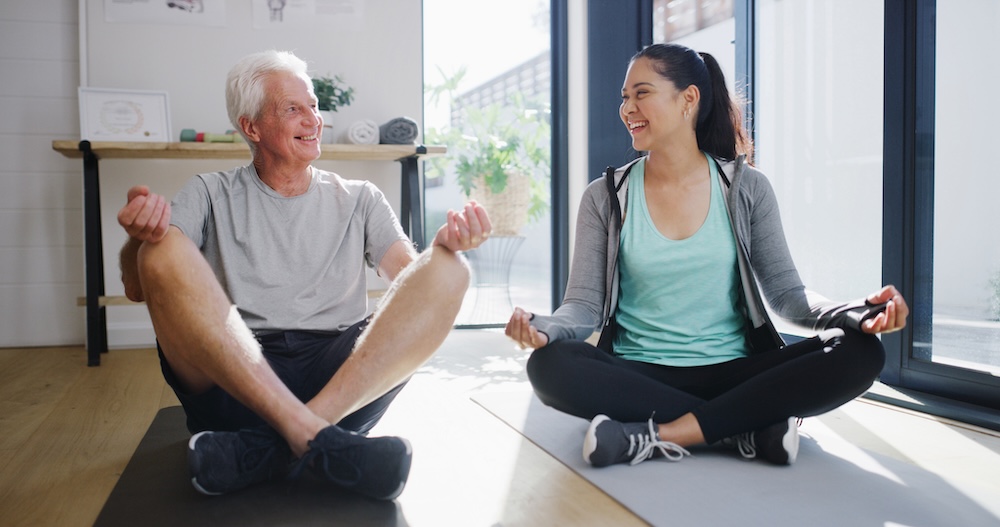 A woman caring for someone with dementia and heart disease exercises with the man in her care.