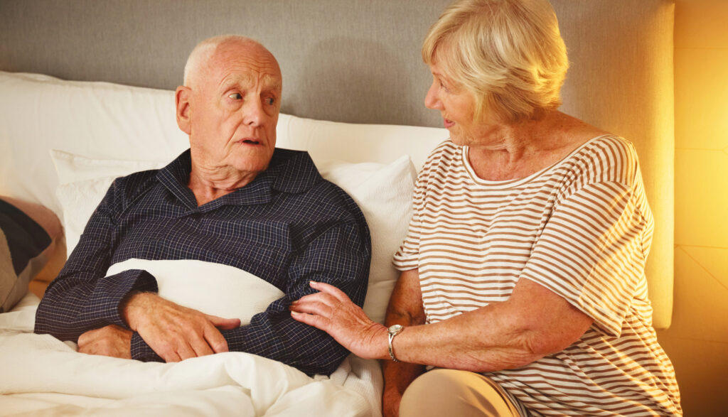 A woman comforts her husband on the first night home after a hospital stay.
