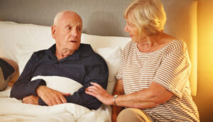 A woman comforts her husband on the first night home after a hospital stay.