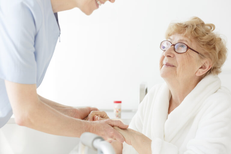A caregiver helps an older woman reduce the risk of hospital readmissions.