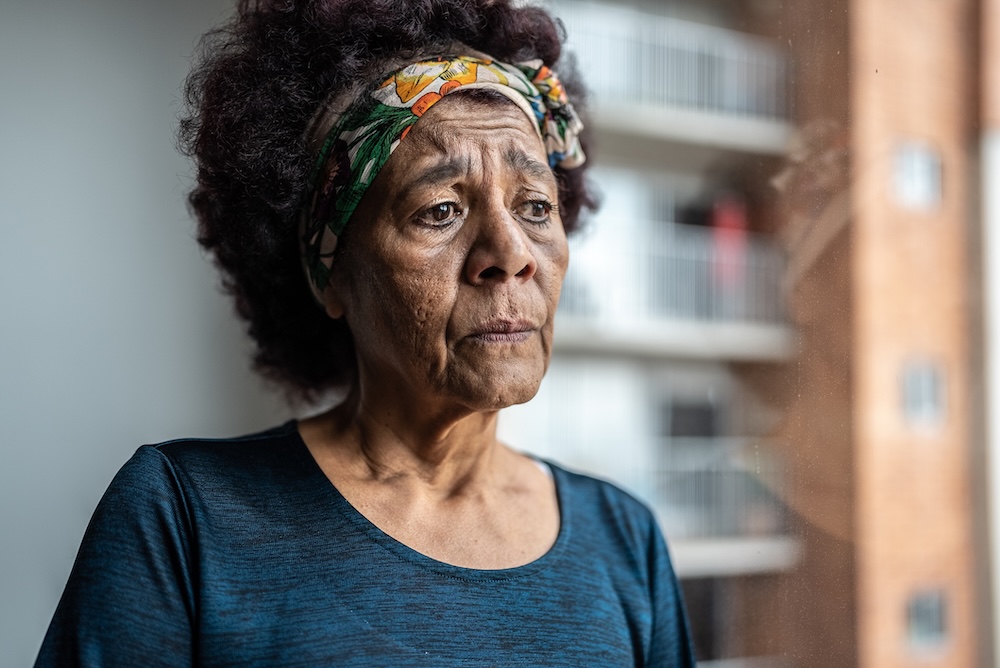 A woman displaying dementia behavior changes related to pain gazes sadly into the distance.