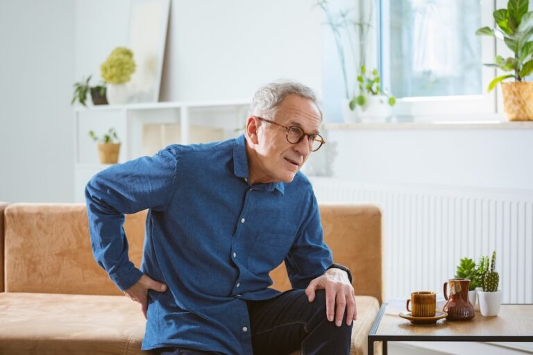 A man struggling with senior chronic pain twists to reach his back.